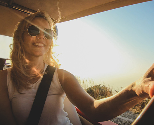 Woman smiling while driving her car in the sun